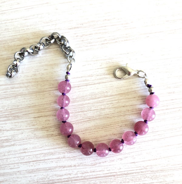 Strawberry jam colored jade beads are hand knotted on royal purple silk.
