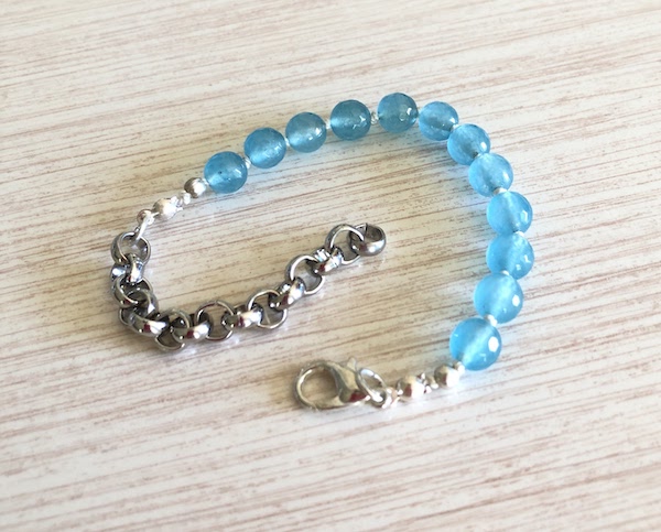 Tropical, aqua blue beads are hand knotted on white silk.