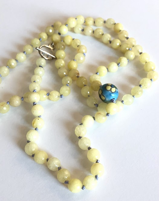 Light yellow, faceted jade gemstone necklace, hand knotted on lavender silk and finished with a silver toggle clasp. Necklace features one hand painted ceramic bead too!