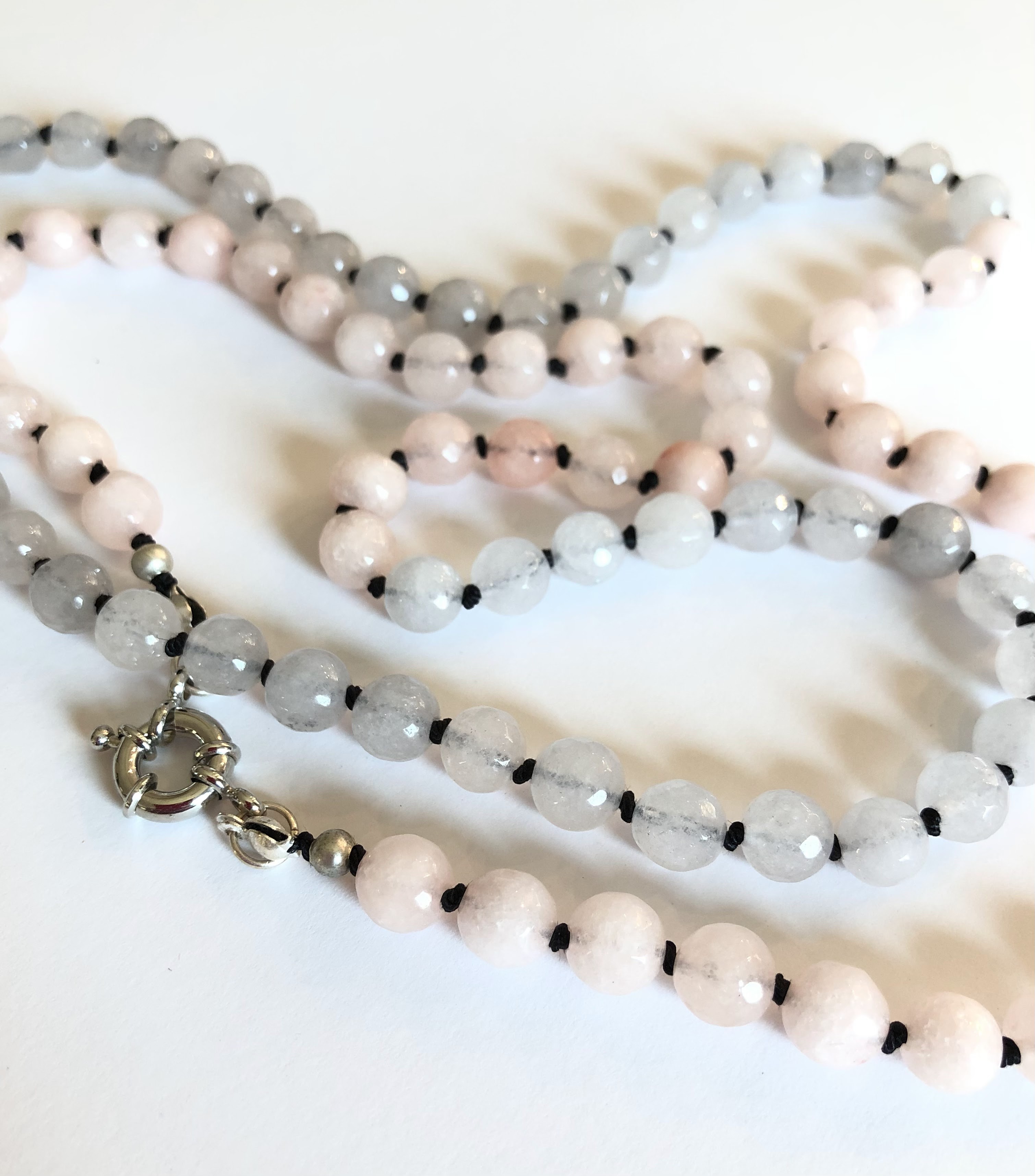 Two-tone light pink and gray, faceted jade gemstone necklace, hand knotted on black silk and finished with silver clasp.