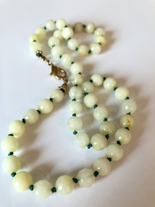 Yellow faceted beads, hand knotted on green silk